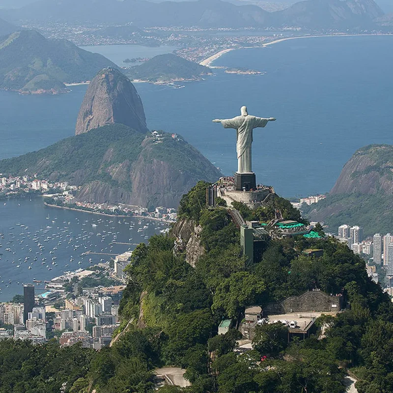 Vista aérea da parte de trás do Cristo Redentor, com a Baía da Guanabara ao fundo.